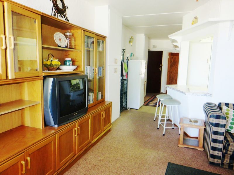 Open plan living area featuring built-in cabinetry and a breakfast bar, with carpeted flooring throughout.