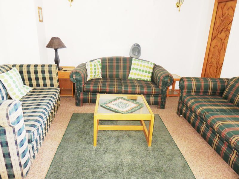 A living room area featuring neutral walls, carpeted flooring, and traditional wooden door detailing.