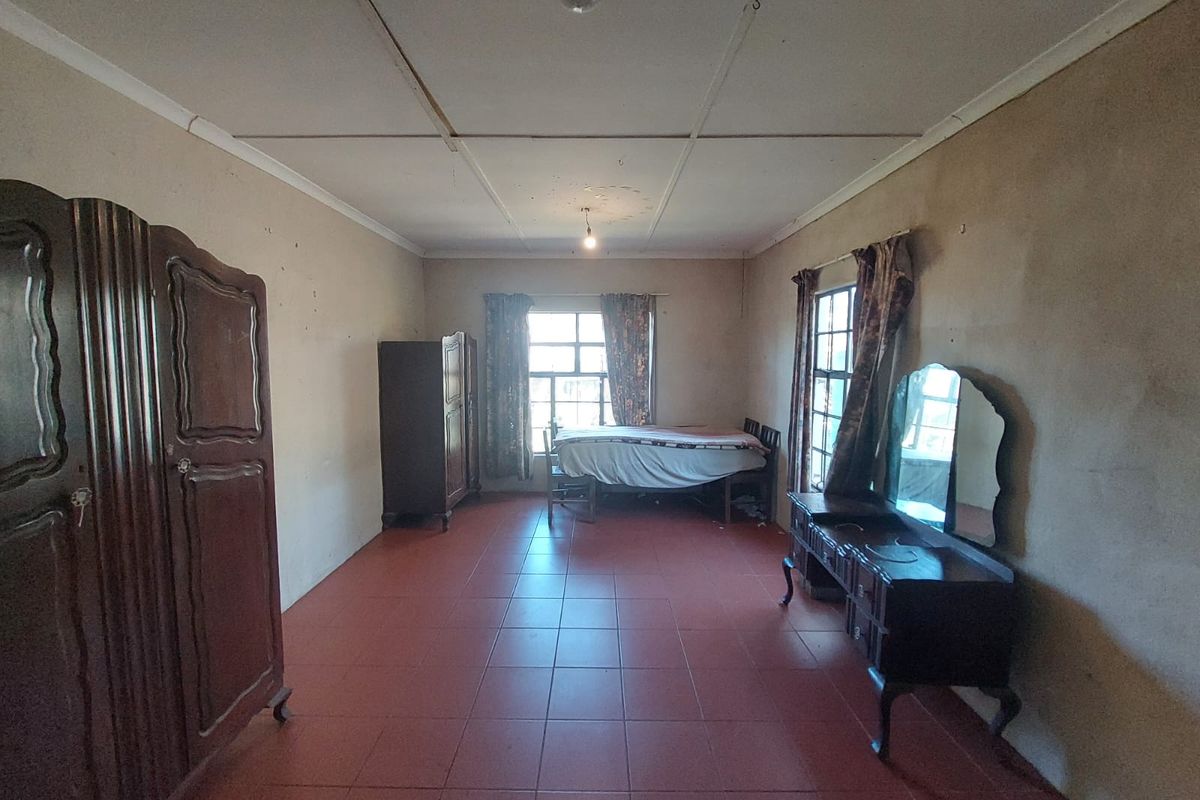 A spacious bedroom featuring tiled flooring and large windows, currently requiring cosmetic updates to the walls and ceiling to improve its overall condition.
