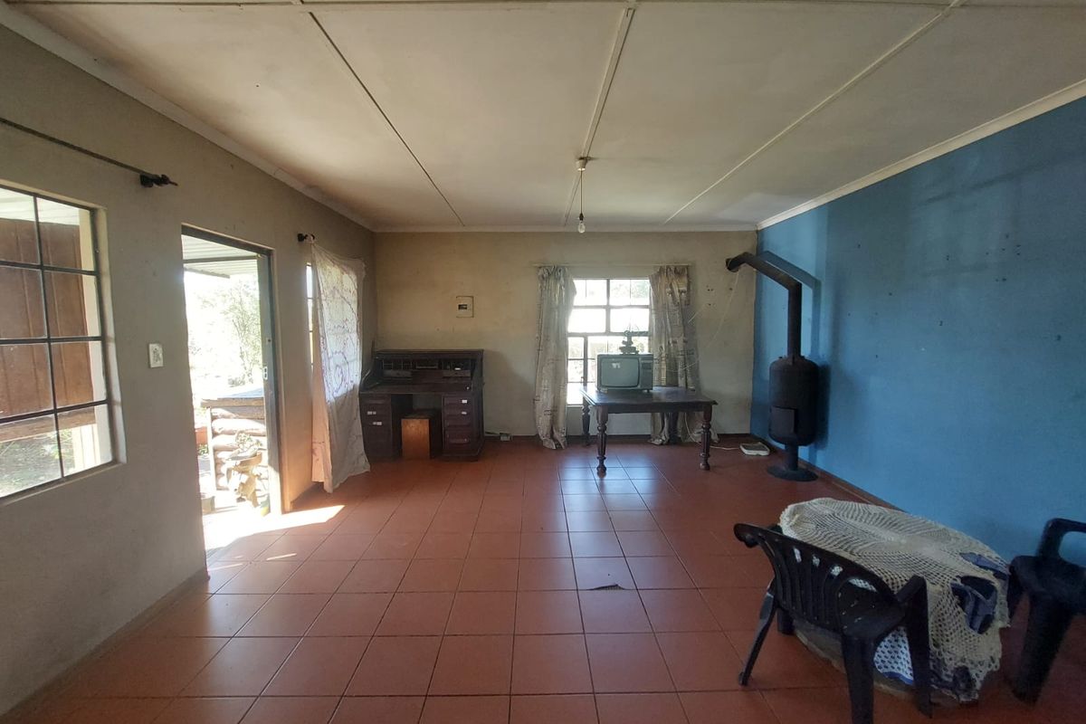 Spacious living area featuring tiled flooring, a freestanding fireplace, and direct access to the exterior, offering a blank canvas for renovation.