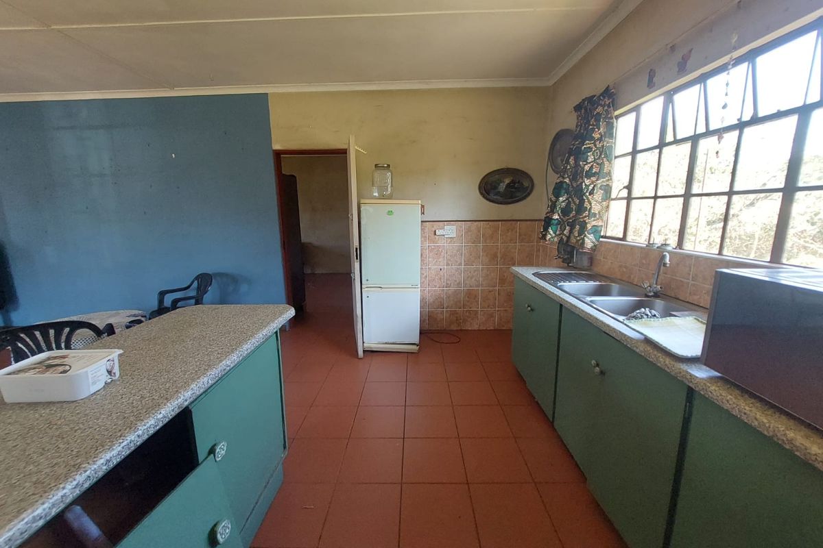 A functional kitchen featuring green cabinetry, laminate countertops, a double bowl sink, and tiled splashbacks, offering potential for a modern renovation.