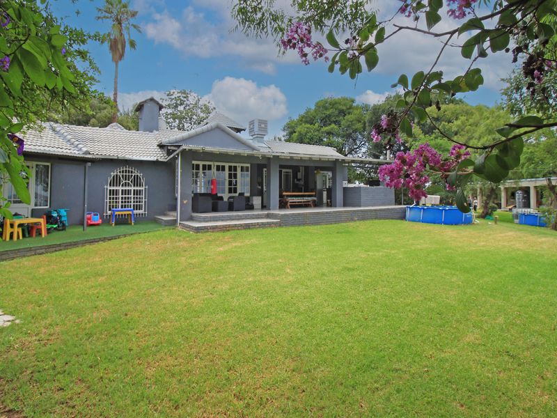 Rear view of the house featuring a spacious lawn, a covered patio area, and a tiled roof structure.