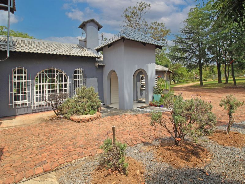 Front exterior view of the house featuring a brick paved driveway, arched entrance, and tiled roof with security bars on the windows.