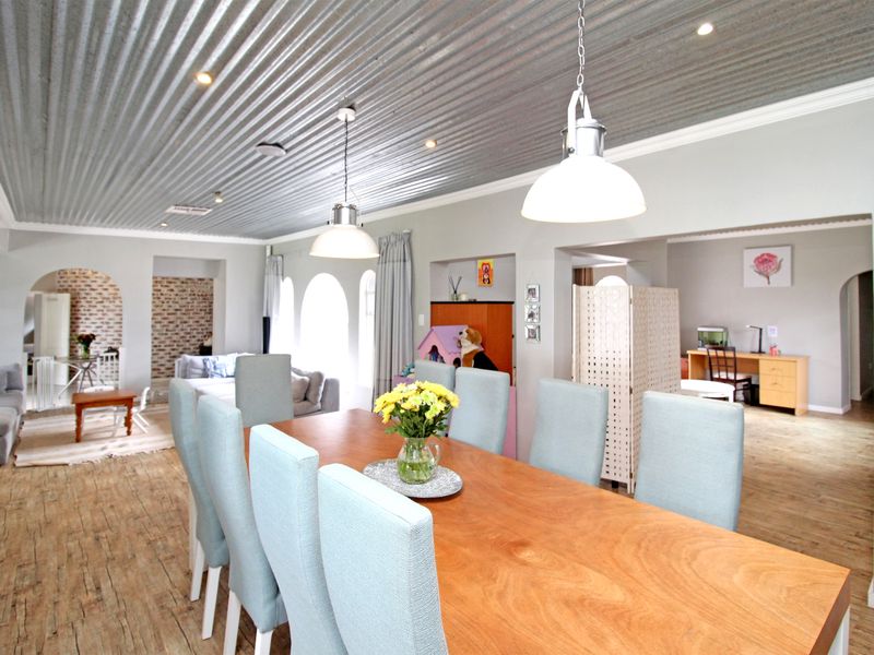 Spacious open-plan living and dining area featuring a unique corrugated metal ceiling, recessed lighting, and arched transitions between connected living spaces.