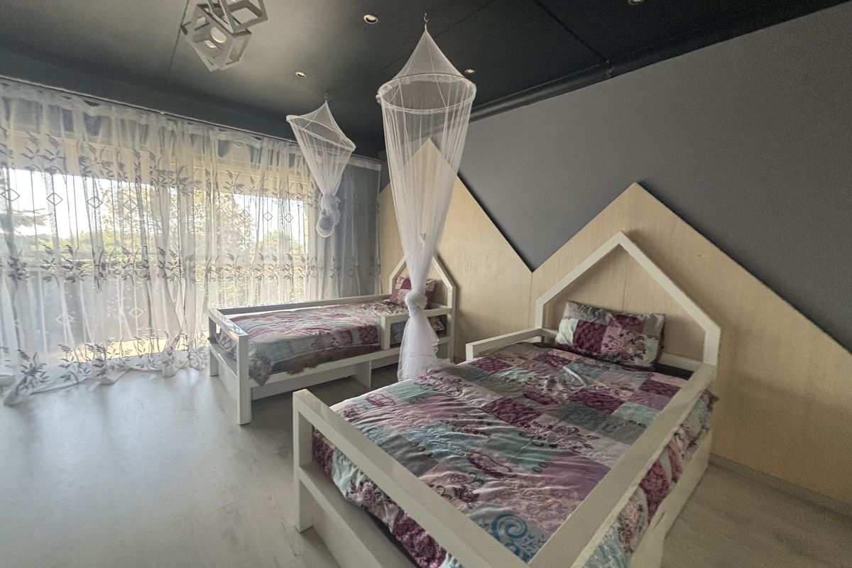 A spacious bedroom featuring custom timber wall paneling, dark ceiling with recessed lighting, and large sliding glass doors providing ample natural light.