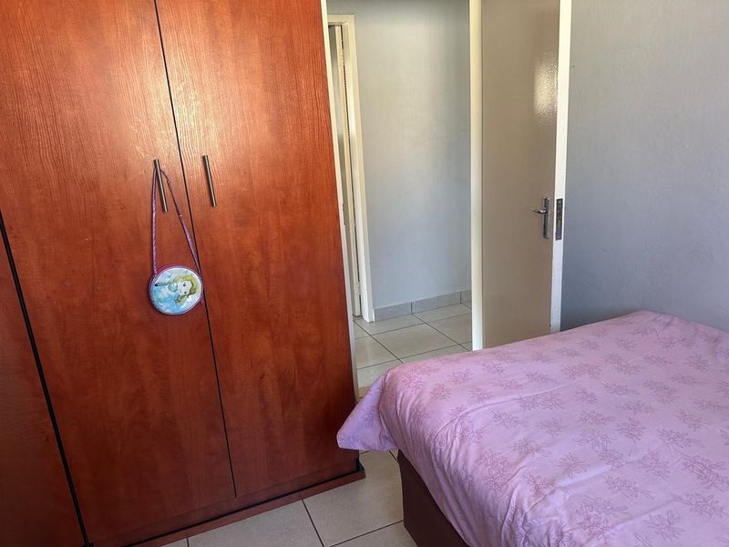 A functional bedroom featuring tiled flooring and a built-in wooden wardrobe, providing essential storage space.