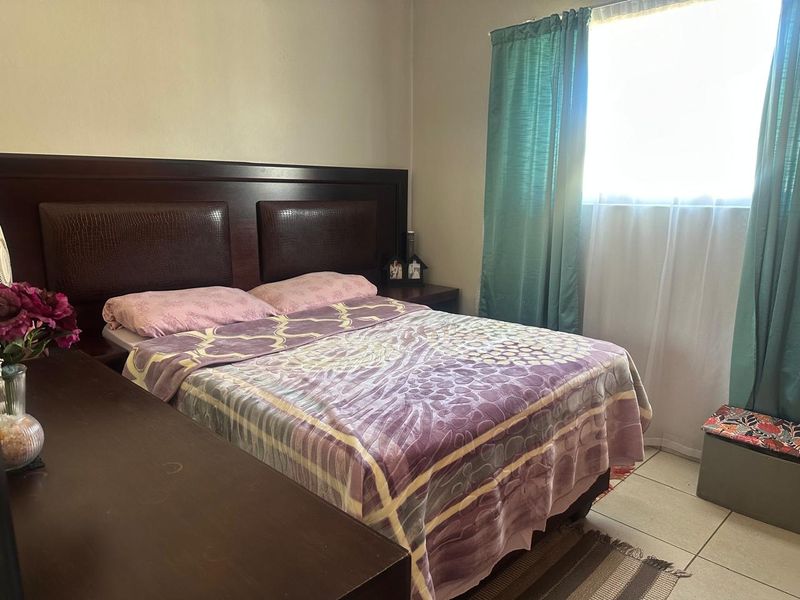 A functional bedroom featuring tiled flooring and a window with curtains, providing a neutral space ready for personalization.