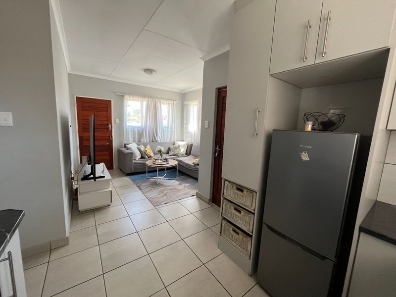 An open-plan living area featuring tiled flooring, neutral wall tones, and built-in cabinetry, creating a functional and connected space.