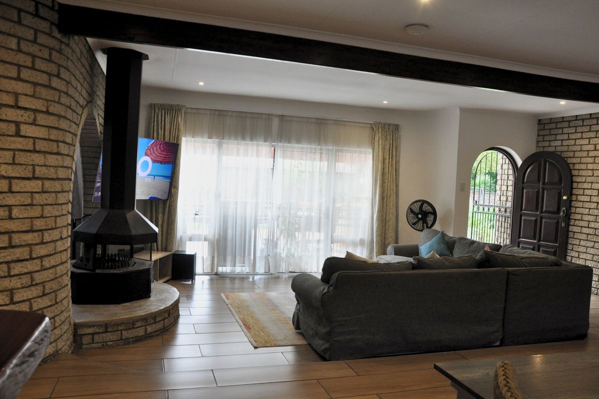 Spacious living area featuring a prominent freestanding fireplace, exposed brickwork, tiled flooring, and large sliding doors leading to the outdoor space.