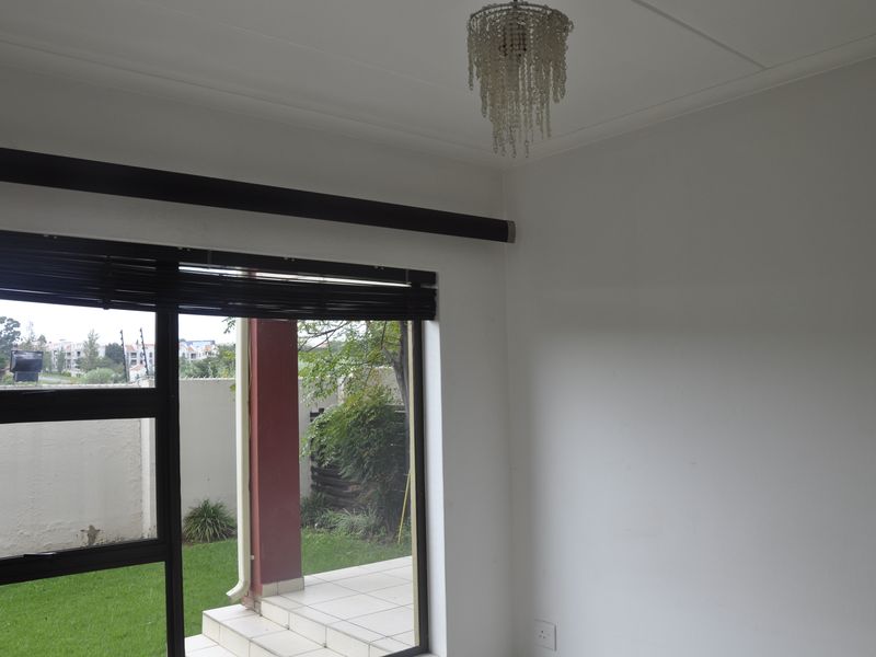 A bright living area featuring large sliding glass doors that open onto a private patio and garden space.