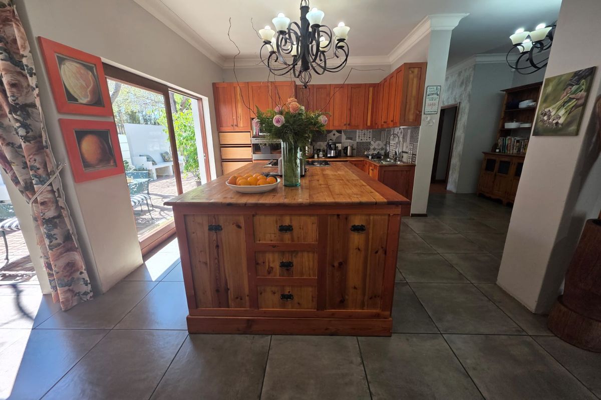 Spacious kitchen featuring a large wooden central island, ample cabinetry, tiled flooring, and direct access to an outdoor patio area.