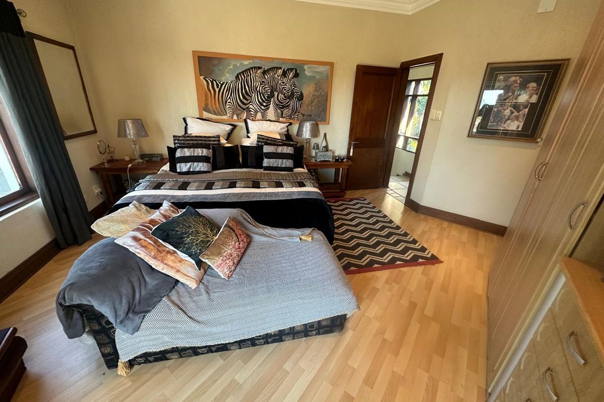 A well-proportioned bedroom featuring light laminate flooring, coved ceilings, and built-in storage cupboards, offering a functional and comfortable living space.