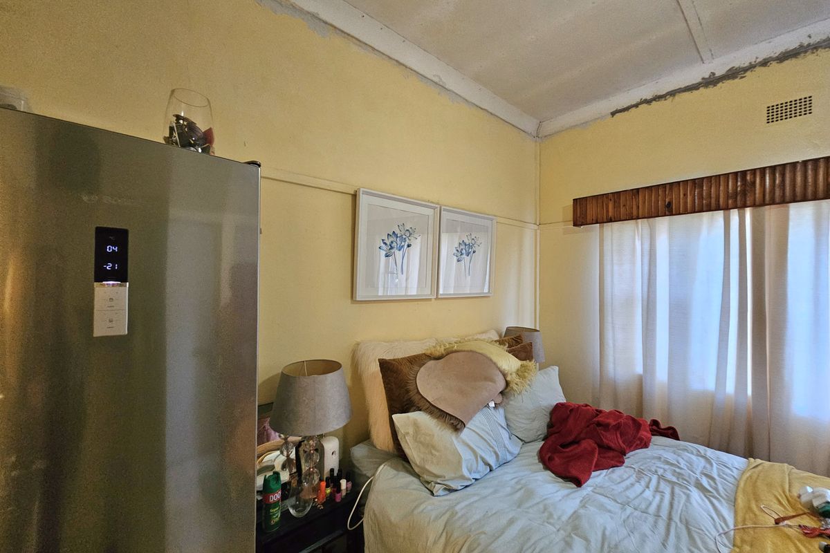 A bedroom featuring a window with a wooden pelmet and visible ceiling trim work requiring finishing.