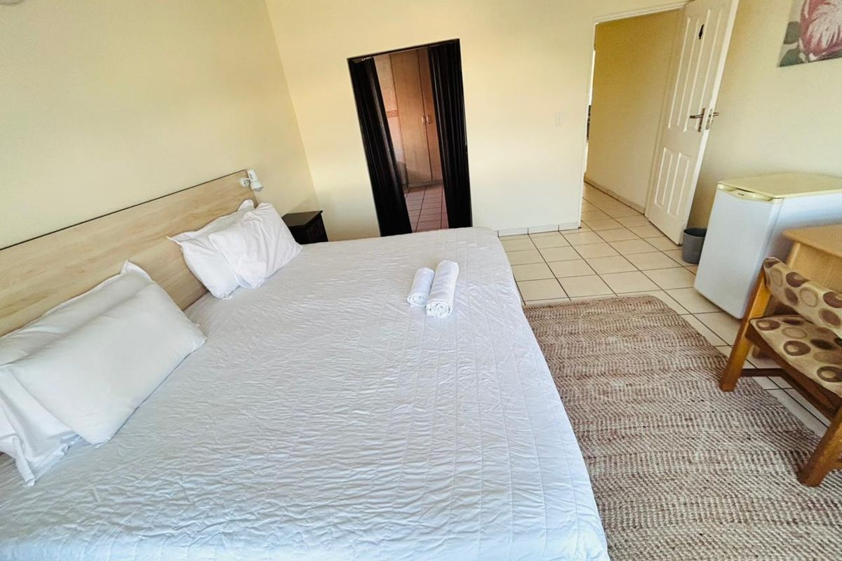 A functional bedroom featuring tiled flooring and a built-in headboard, providing a simple and practical living space.