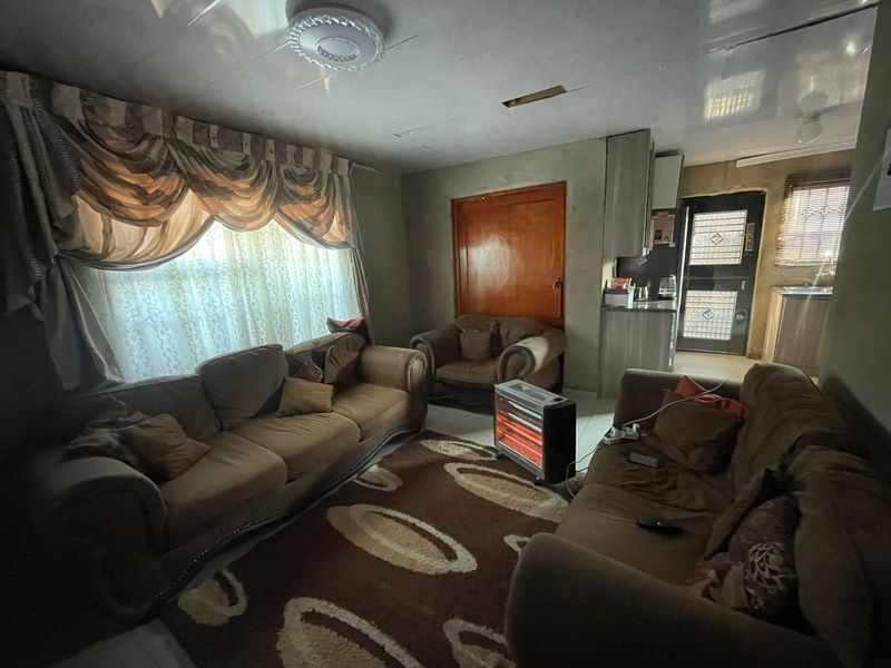 Open plan living area featuring tiled flooring, integrated kitchen cabinetry, and direct access to an exterior door.
