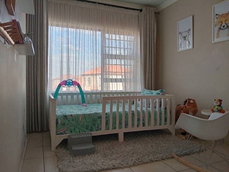 A bedroom featuring tiled flooring and a large window with installed curtain tracks, providing natural light to the space.