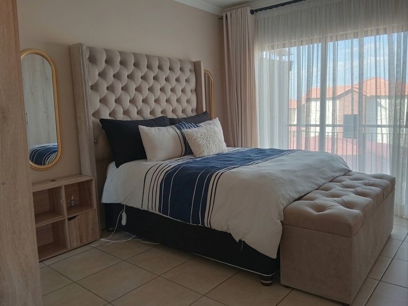 A well-maintained bedroom featuring tiled flooring and a large sliding glass door that provides access to an outdoor balcony area.