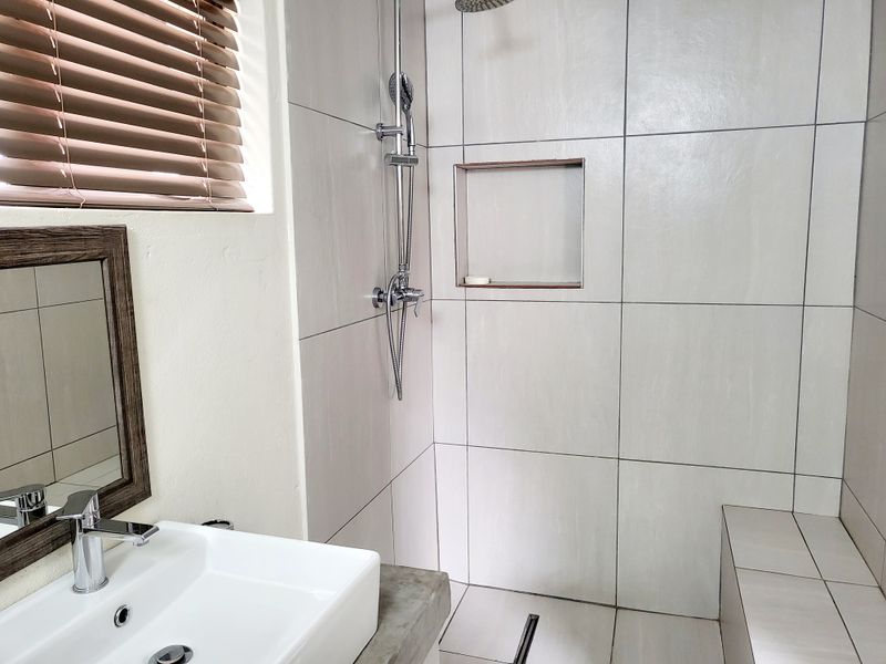 Modern bathroom featuring a tiled shower enclosure with a built-in niche, concrete vanity top, and contemporary basin mixer.