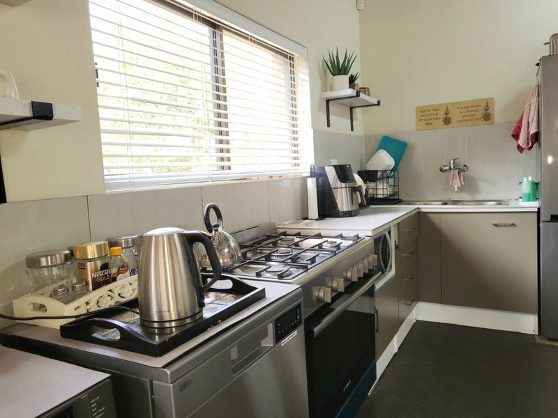 A functional kitchen featuring a gas hob, built-in oven, stainless steel sink, and neutral cabinetry with tiled splashbacks.