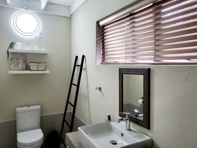 A well-maintained bathroom featuring a modern vessel sink on a concrete vanity, a wall-mounted mirror, and a toilet with neutral wall finishes.