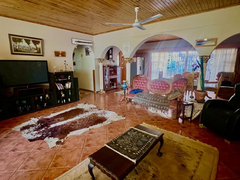 Spacious open-plan living area featuring timber ceilings, ceramic floor tiles, and distinctive arched architectural details connecting to the dining space.