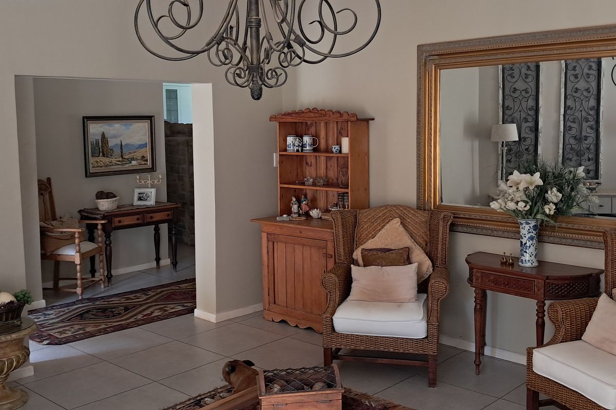 A well-maintained living room featuring neutral wall tones, tiled flooring, and an ornate chandelier, providing a comfortable and inviting atmosphere.