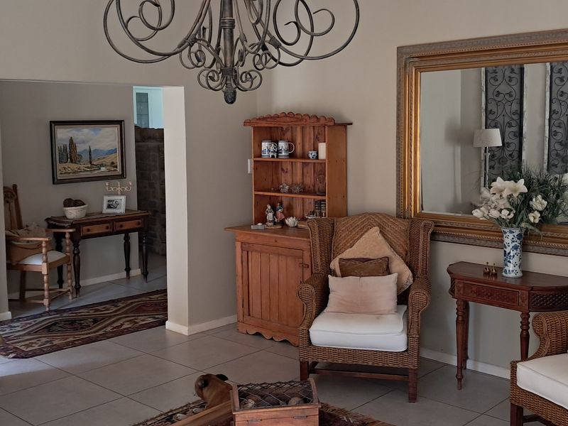 A well-maintained living room featuring neutral wall tones, tiled flooring, and an ornate chandelier, providing a comfortable and inviting atmosphere.