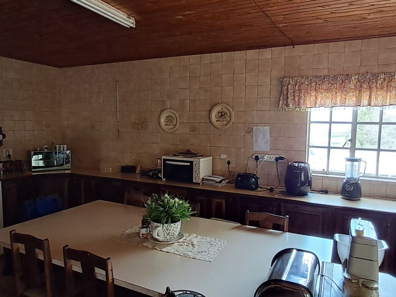 A dated kitchen featuring timber ceilings, tiled walls, and extensive built-in cabinetry, offering significant potential for a modern renovation.