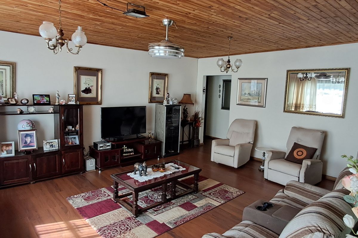 Spacious living room featuring a warm timber-paneled ceiling and laminate flooring, providing a comfortable and traditional living space.