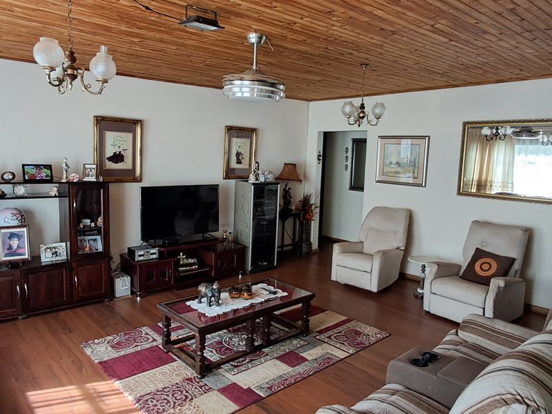 Spacious living room featuring a warm timber-paneled ceiling and laminate flooring, providing a comfortable and traditional living space.