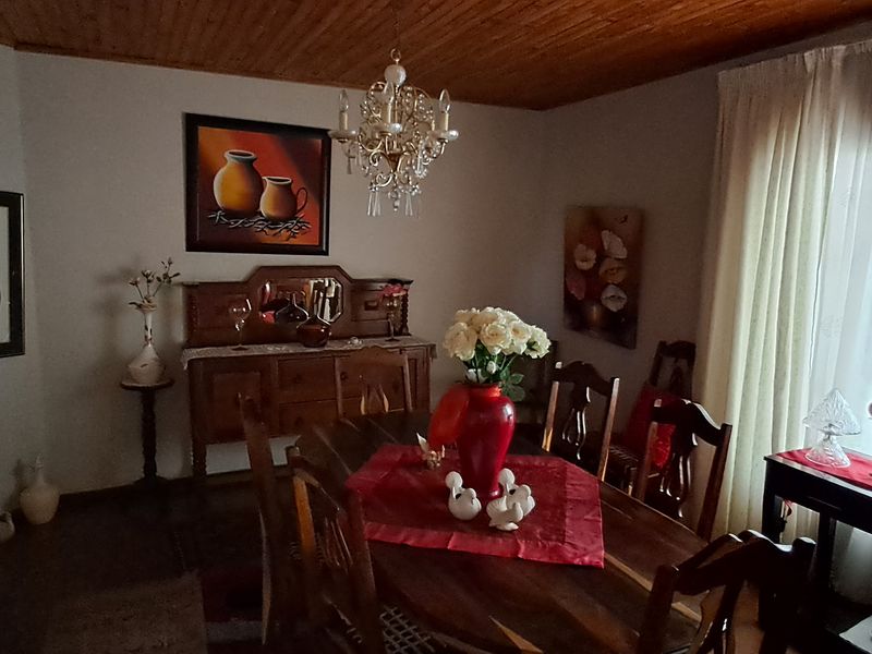 A traditional dining room featuring a warm timber-paneled ceiling and a classic crystal chandelier, providing a cozy atmosphere for formal meals.