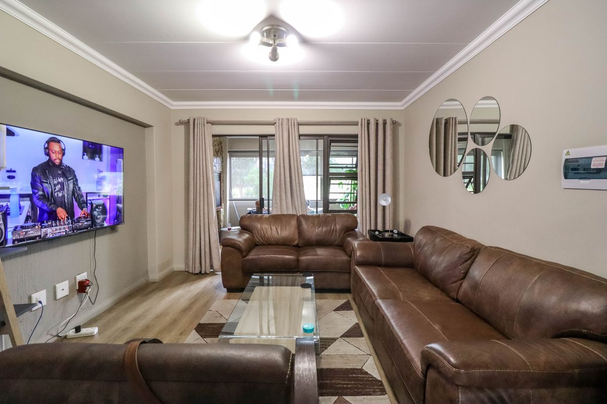 A well-maintained living room featuring laminate flooring, decorative ceiling molding, and sliding glass doors providing access to the outdoor area.
