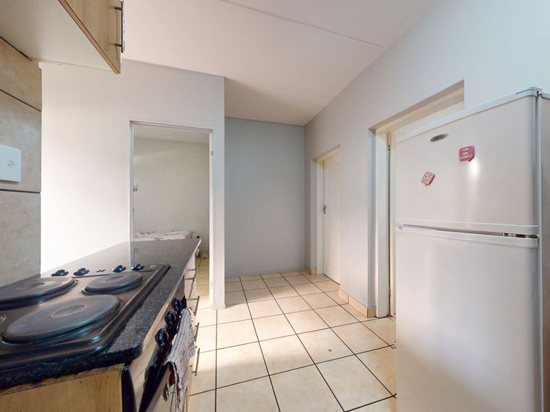 A functional kitchen featuring tiled flooring, granite countertops, and a built-in stove, providing a practical workspace with direct access to adjacent rooms.