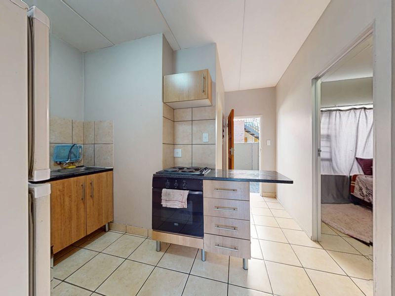 A functional kitchen featuring tiled flooring, built-in cabinetry, and a freestanding stove, offering a practical layout with direct access to the exterior.