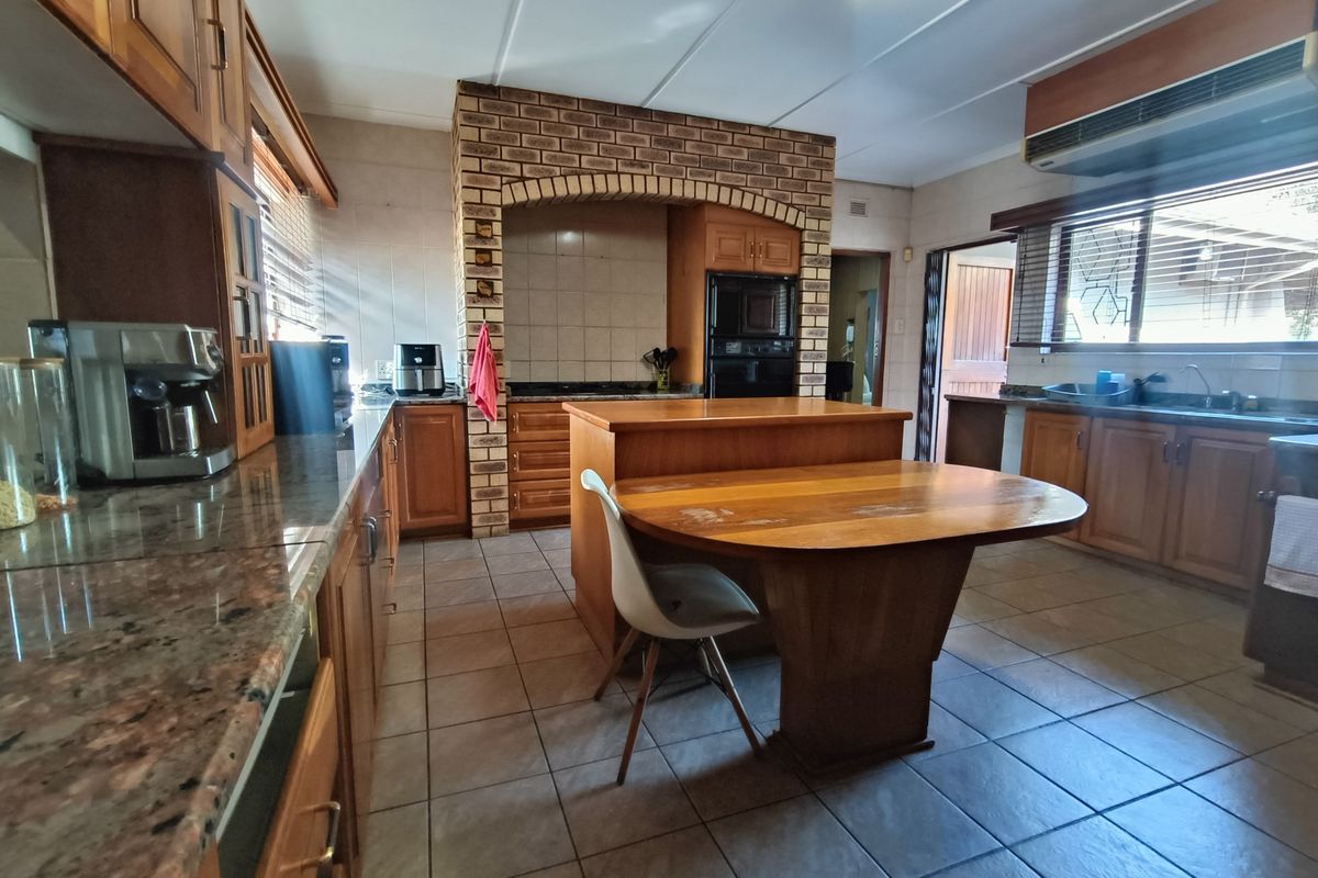 Spacious kitchen featuring wooden cabinetry, granite countertops, a brick feature arch with built-in oven, and tiled flooring.