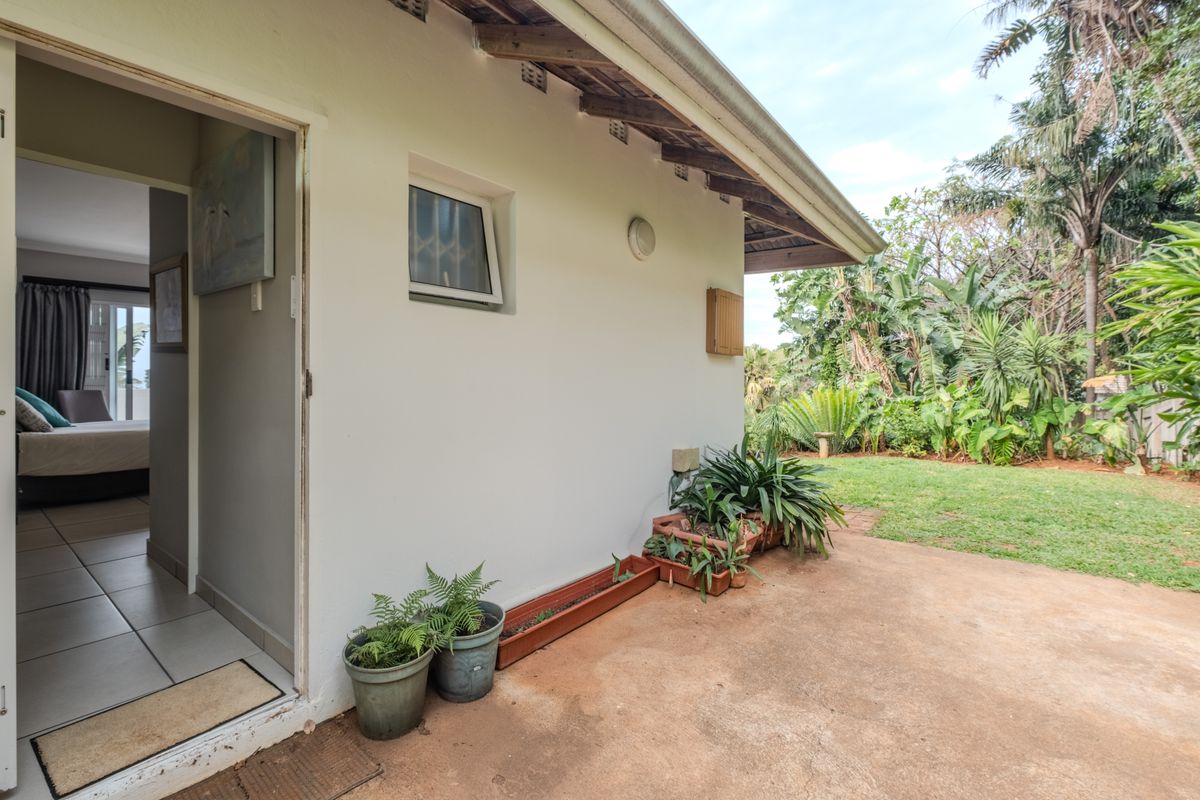 A view of the rear exterior patio area featuring a concrete slab, garden access, and direct entry into a bedroom.