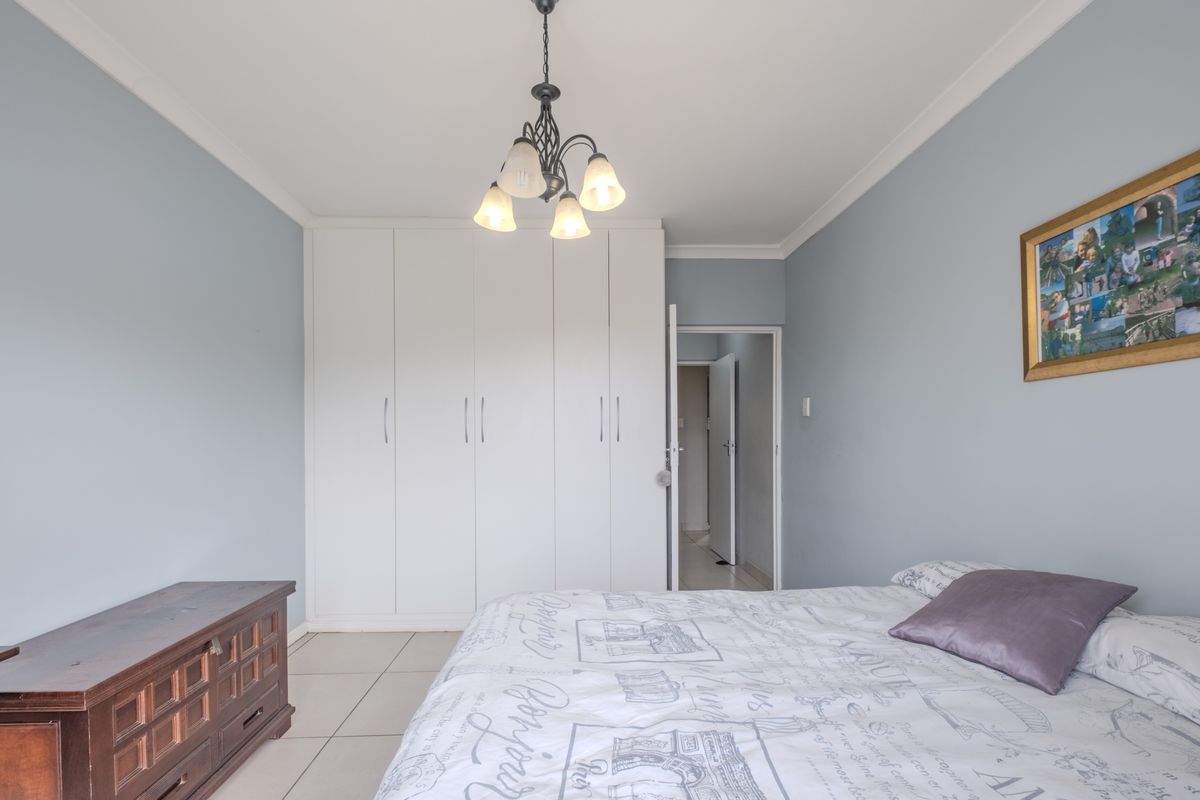 A bedroom featuring built-in floor-to-ceiling wardrobes, tiled flooring, and neutral wall finishes.