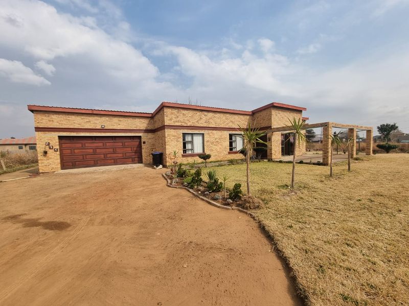 A single-story face brick house featuring a double garage with a wooden door and a covered front patio area.