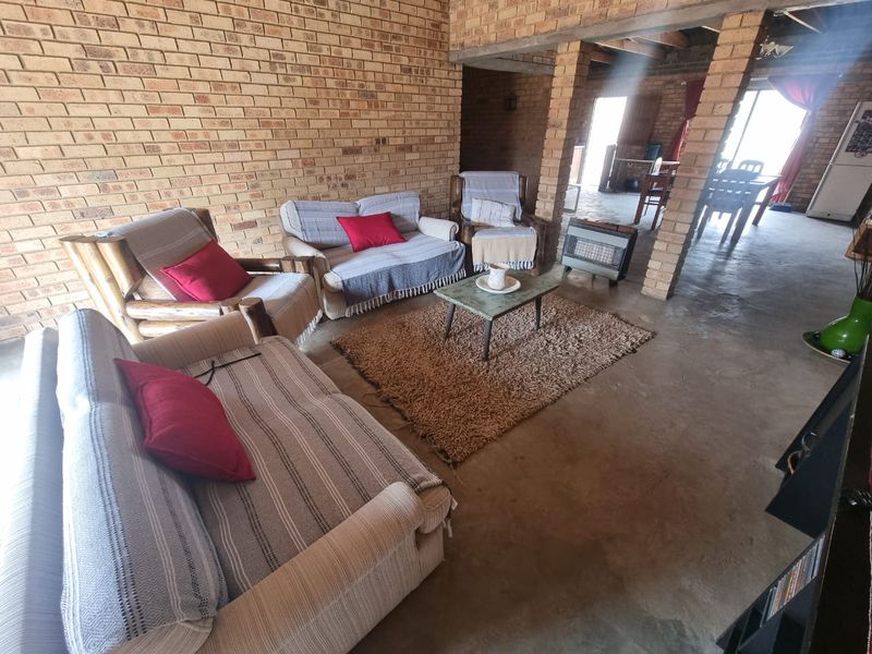 Spacious open-plan living area featuring exposed brick walls, concrete flooring, and rustic timber ceiling beams, offering a blank canvas for renovation.