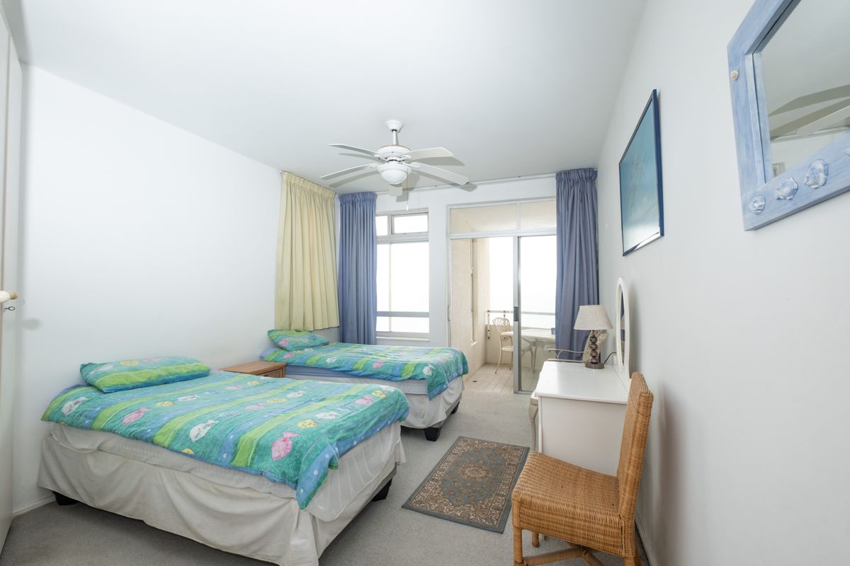 A bedroom featuring neutral carpeting, a ceiling fan, and sliding glass door access to a private balcony.