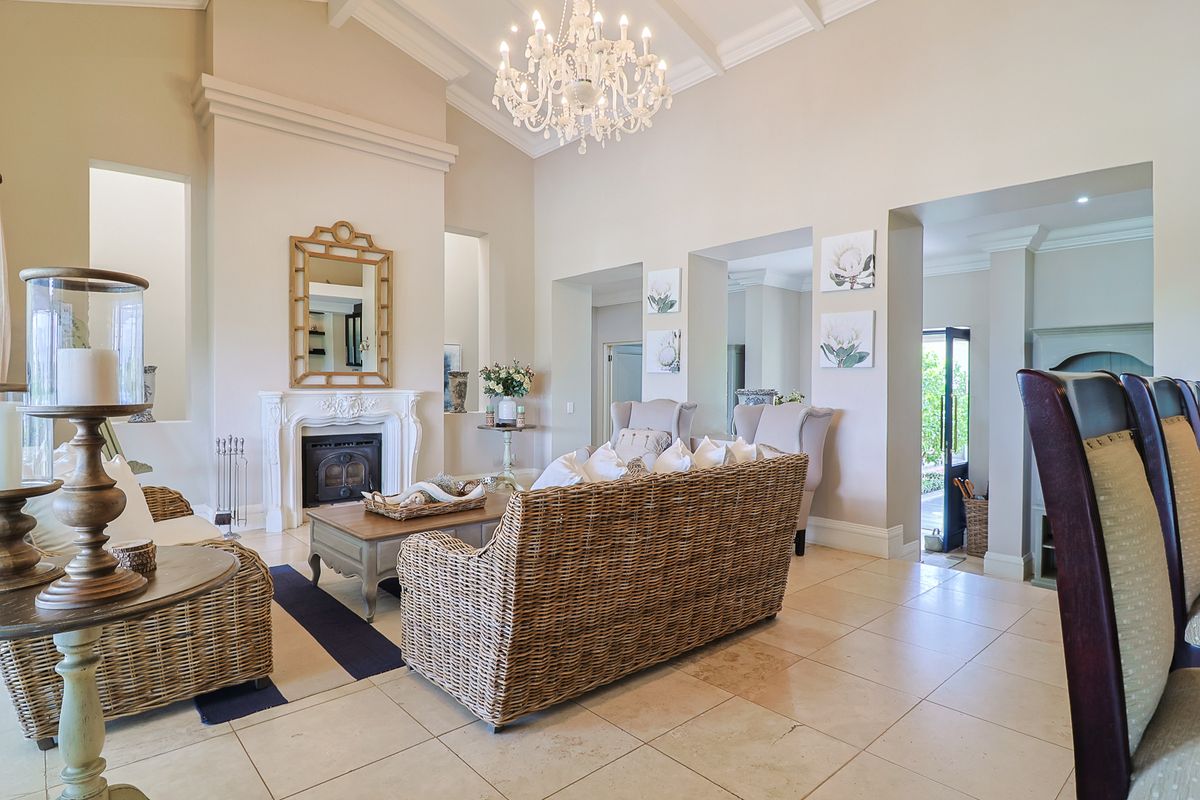 Spacious living room featuring a vaulted ceiling, elegant fireplace with ornate mantelpiece, and neutral stone tile flooring, creating a bright and sophisticated atmosphere.