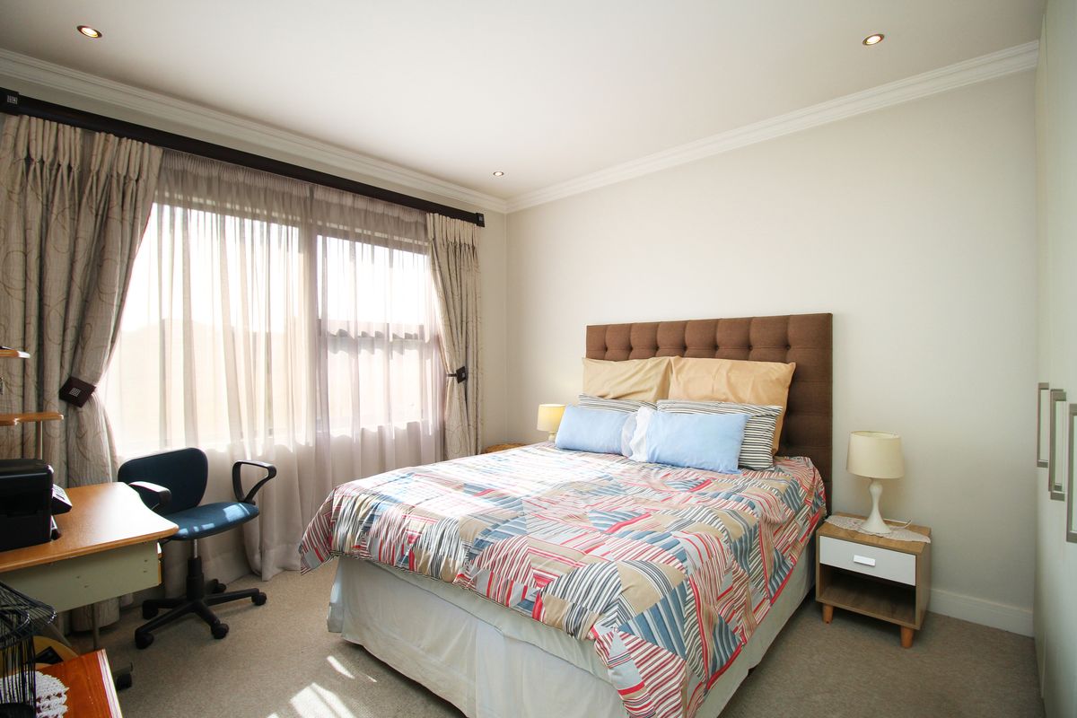 A well-lit bedroom featuring neutral carpeting, recessed ceiling lighting, and built-in cabinetry, offering a comfortable and functional living space.