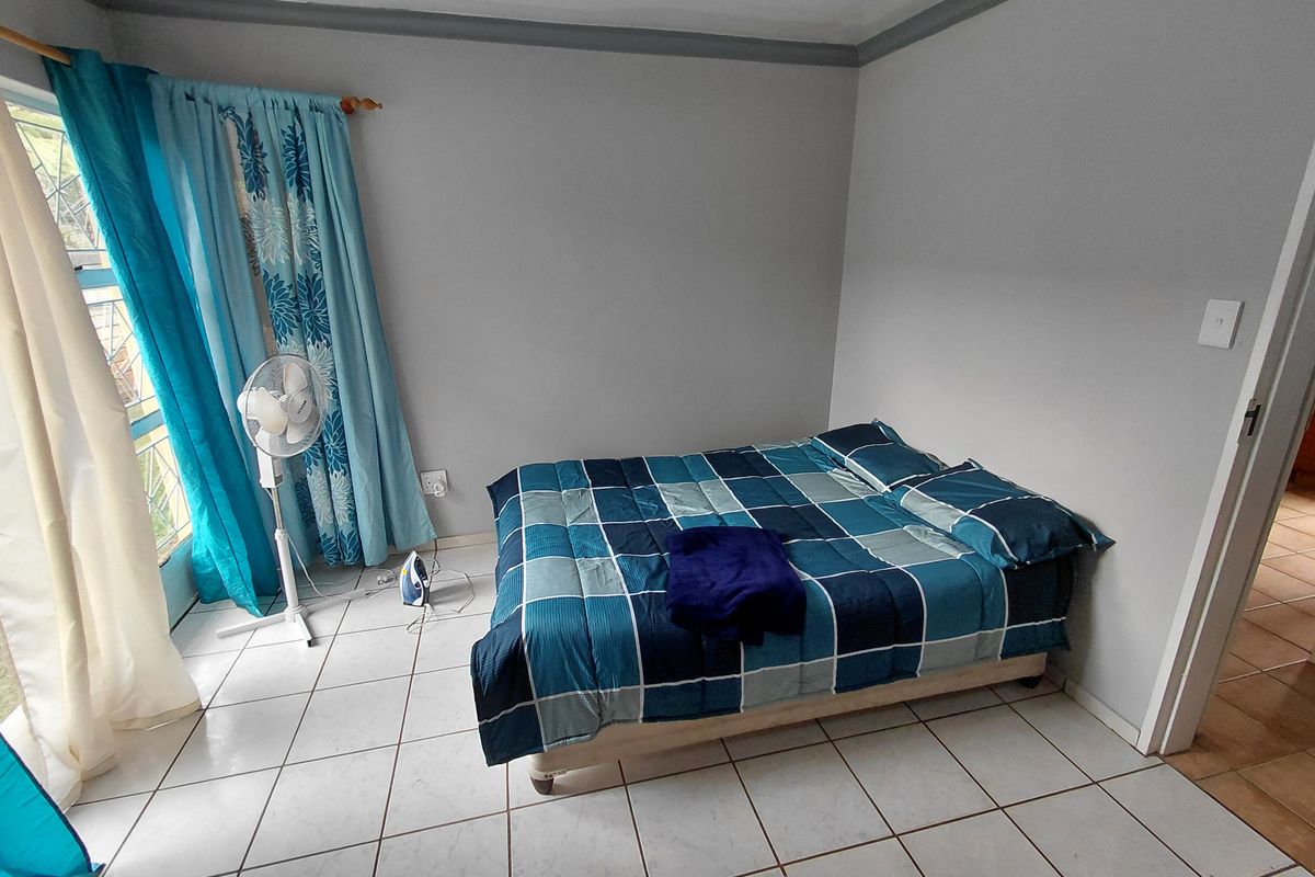 A functional bedroom featuring tiled flooring and access to natural light through a sliding door.