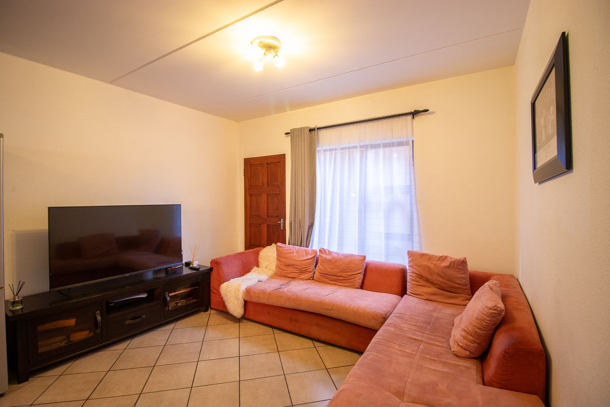 A living room featuring tiled flooring, a ceiling light fixture, and a window with a curtain rod.