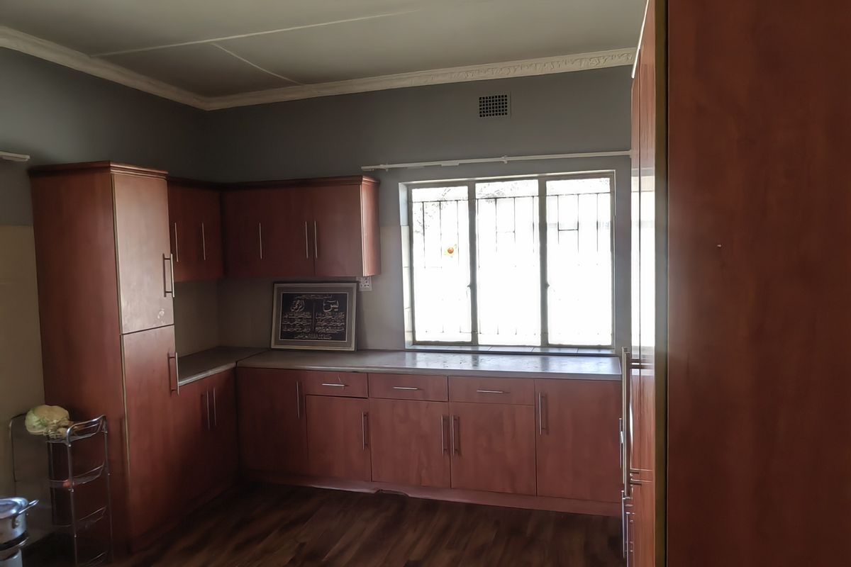 A functional kitchen featuring wood-finish cabinetry, laminate countertops, and durable flooring, offering a practical layout with natural light from the window.