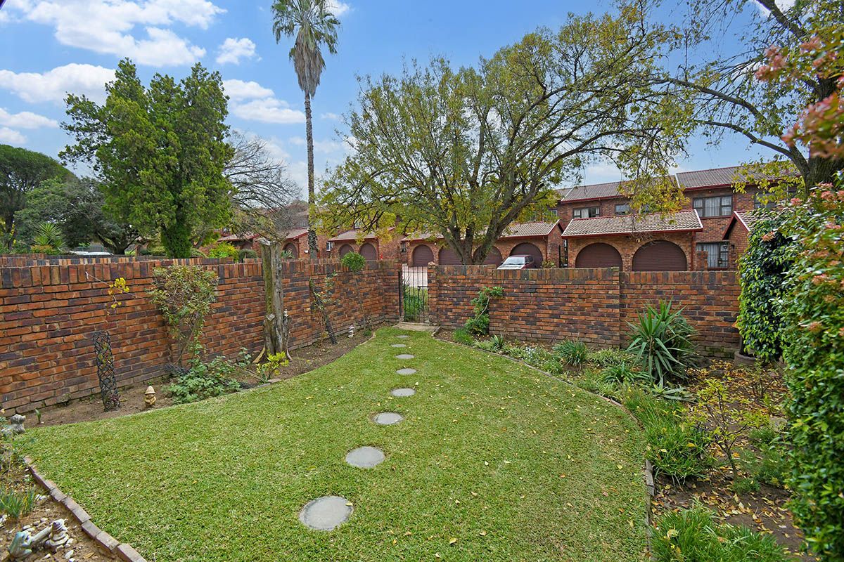A private rear garden featuring a lawn, stone stepping path, and perimeter brick walling, offering a secluded outdoor space.