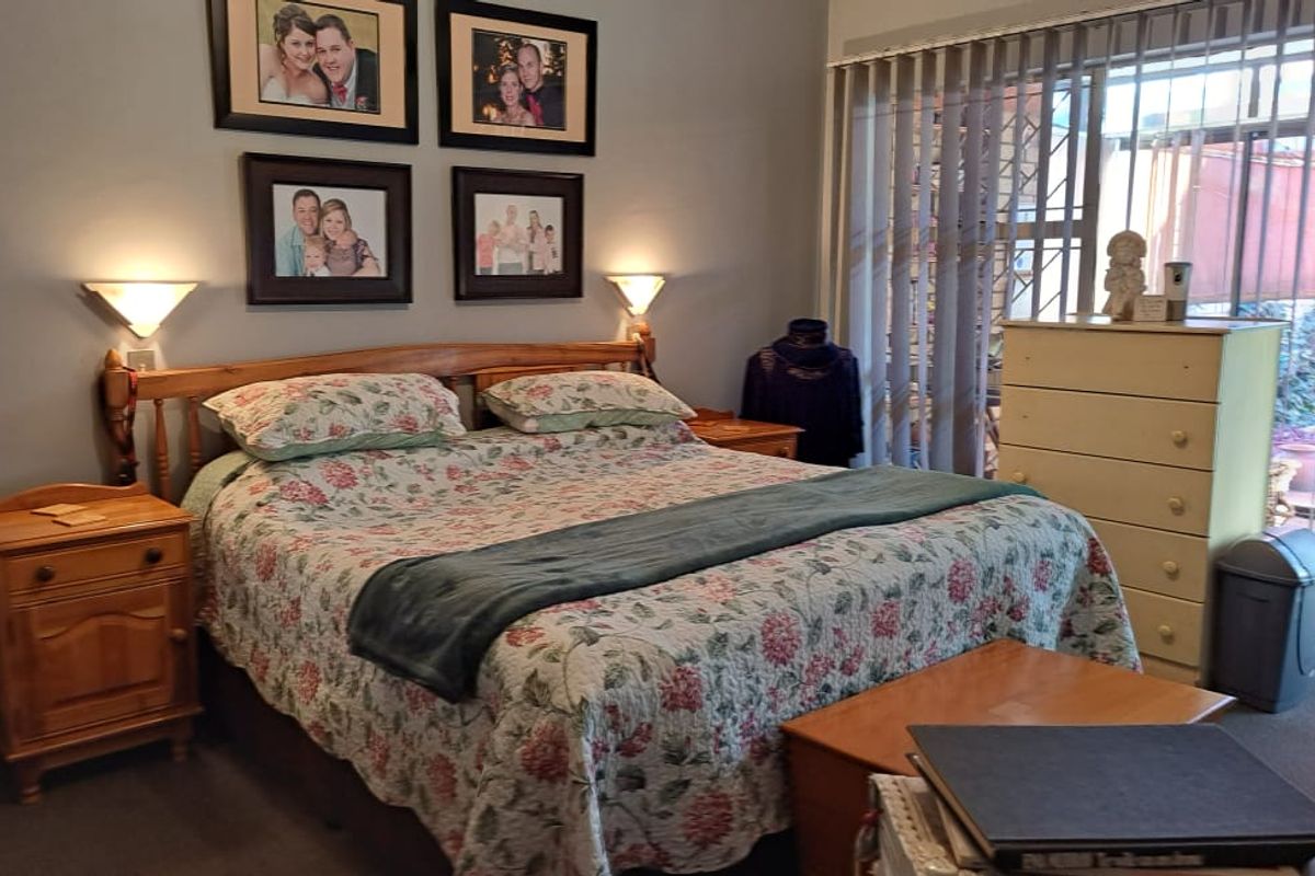 A comfortable bedroom featuring wall-mounted lighting and large sliding glass doors that provide access to an outdoor area.