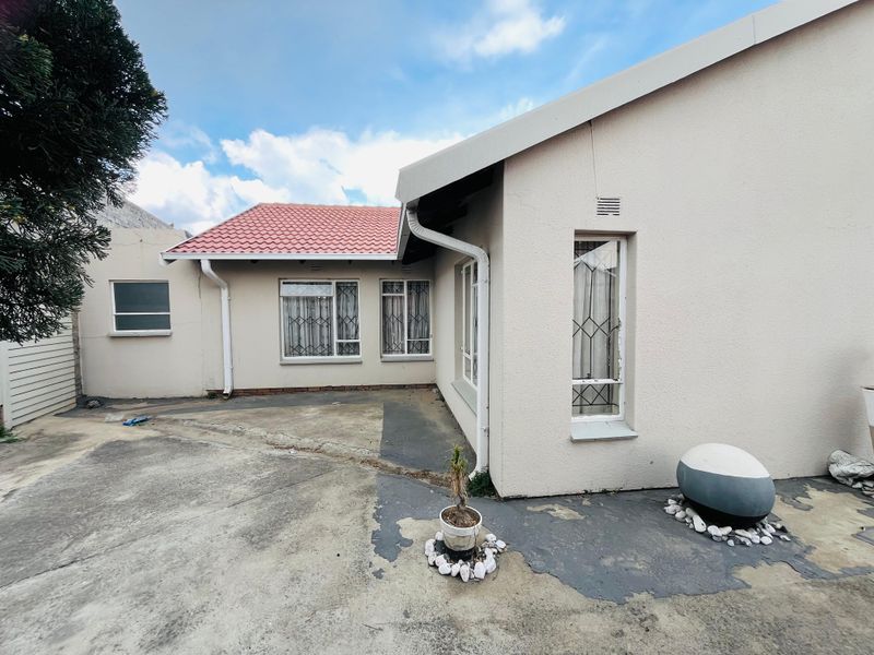 Rear exterior view of the house featuring a concrete patio area, tiled roof, and security bars on the windows.