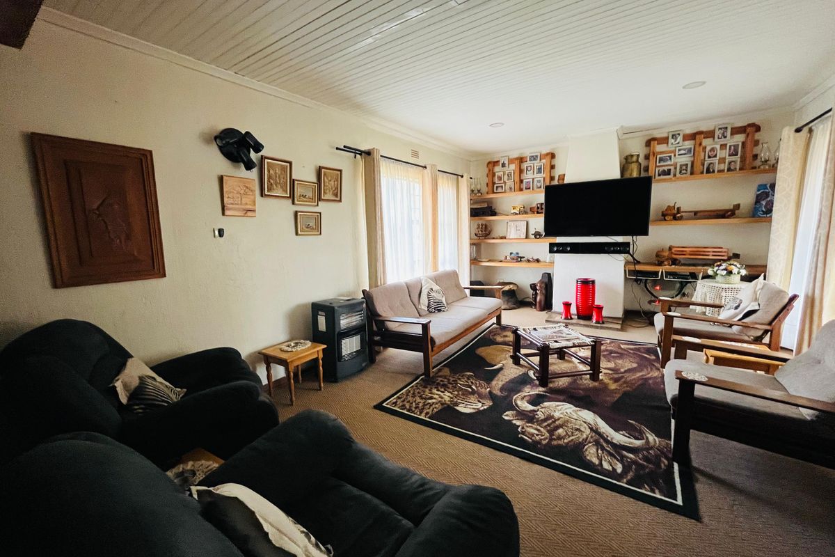 A comfortable living room featuring a built-in fireplace, timber shelving, and a classic tongue-and-groove ceiling.