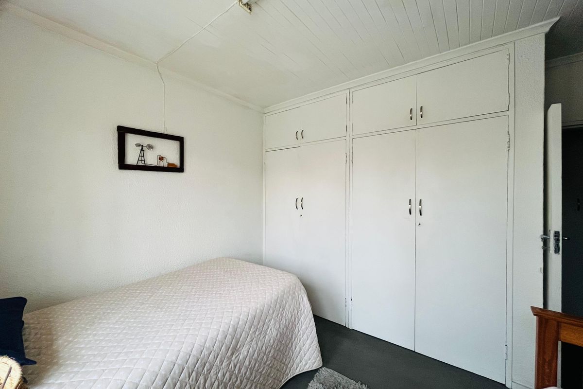 A bedroom featuring built-in cupboards with overhead storage and a white tongue-and-groove ceiling.